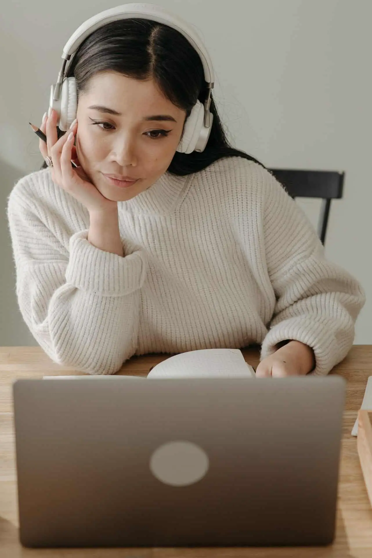 a woman with headphones sitting in front of the laptop screen