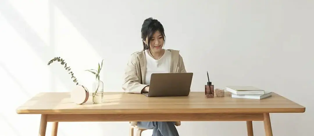 a woman sitting at the table and looking at the laptop