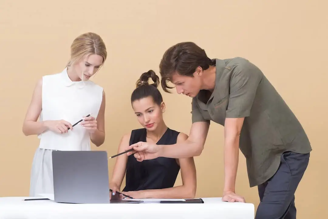 three persons around laptop