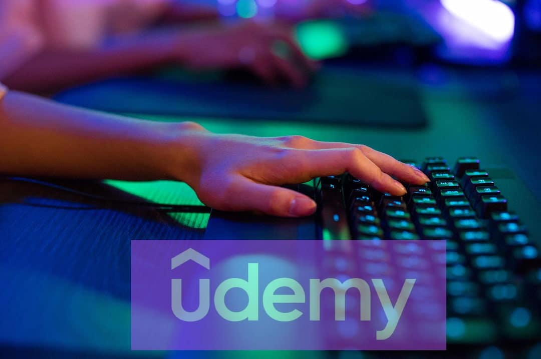 Udemy logo and a closeup of a person's hand on the keyboard